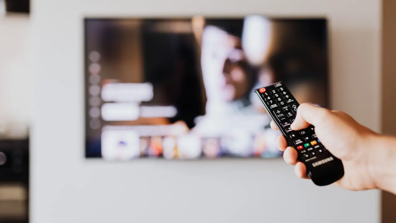 Person browsing IPTV channel guide on a modern television in a cozy living room